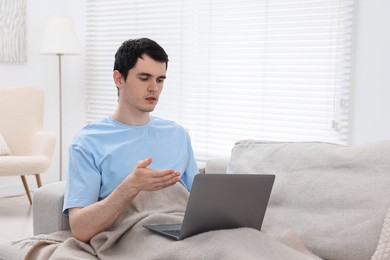 Photo of Sick man having online consultation with doctor via laptop at home