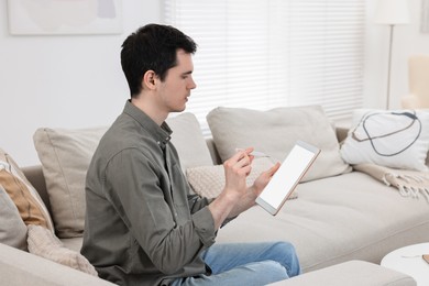 Photo of Sick man with thermometer having online consultation with doctor via tablet at home