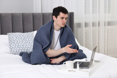 Sick man having online consultation with doctor via laptop at home