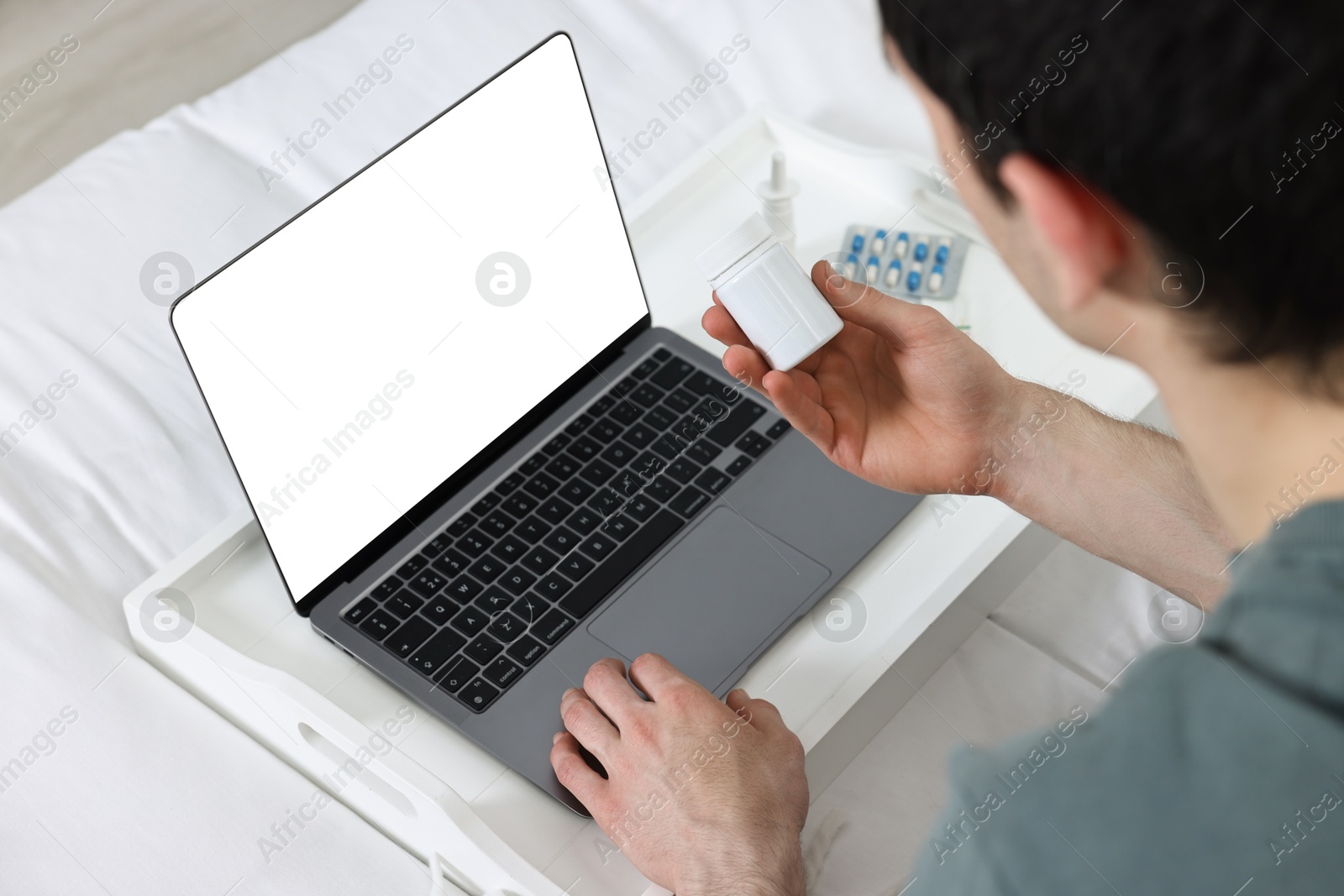 Photo of Sick man with pills having online consultation with doctor via laptop at home, closeup