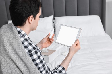 Photo of Sick man with thermometer having online consultation with doctor via tablet at home