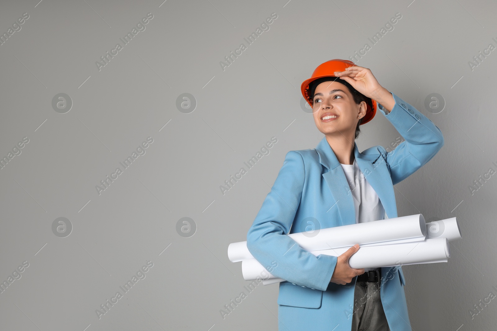 Photo of Engineer in hard hat with drafts on grey background, space for text