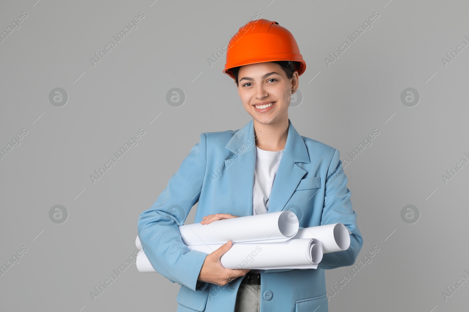 Photo of Engineer in hard hat with drafts on grey background