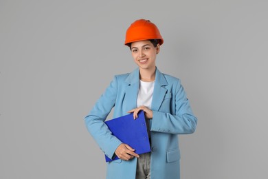 Engineer in hard hat with clipboard on grey background