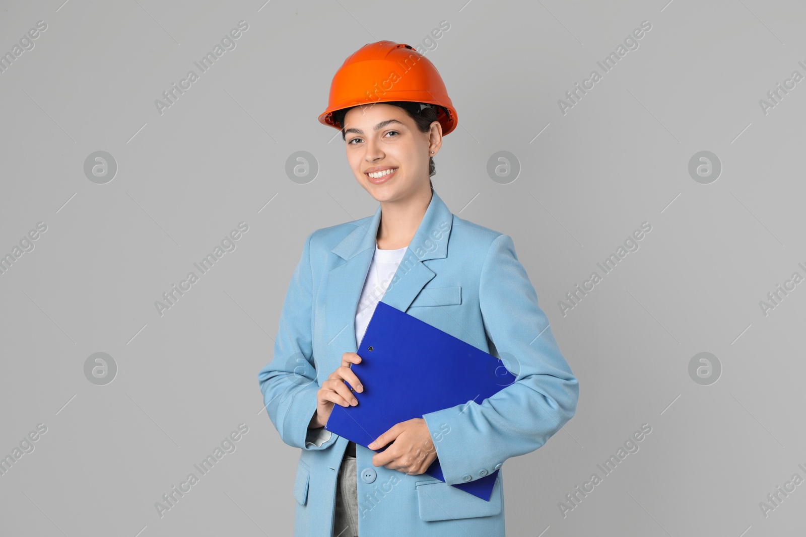 Photo of Engineer in hard hat with clipboard on grey background