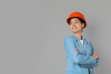 Engineer in hard hat on grey background, space for text