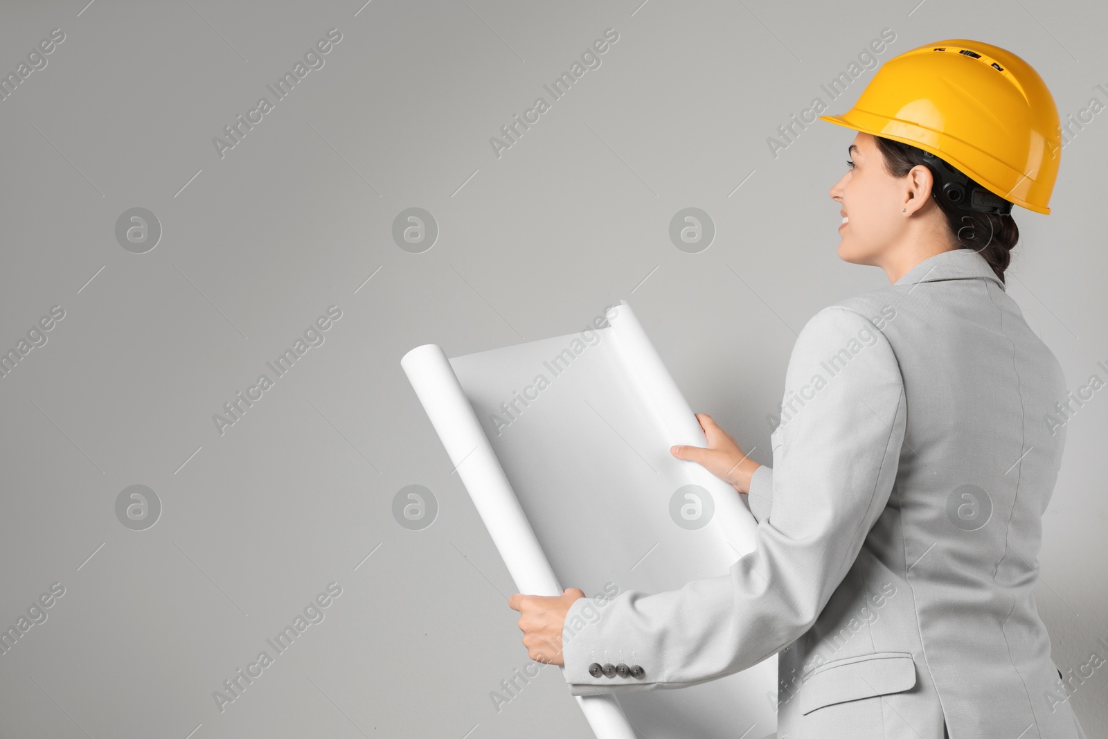 Photo of Engineer in hard hat with draft on grey background, space for text