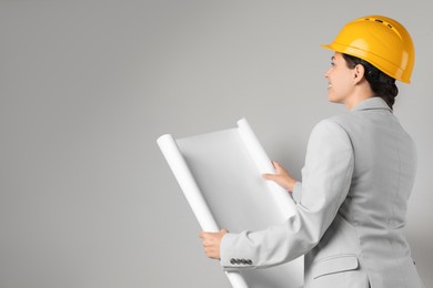 Photo of Engineer in hard hat with draft on grey background, space for text