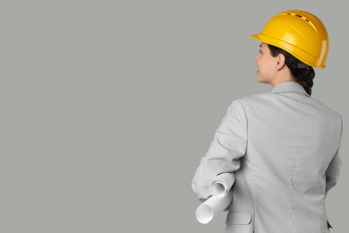 Engineer in hard hat with drafts on grey background, space for text