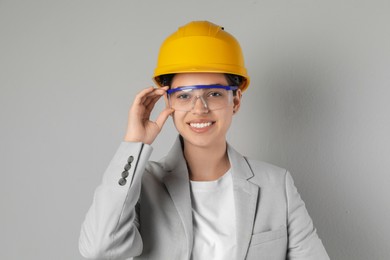 Engineer in hard hat and goggles on grey background