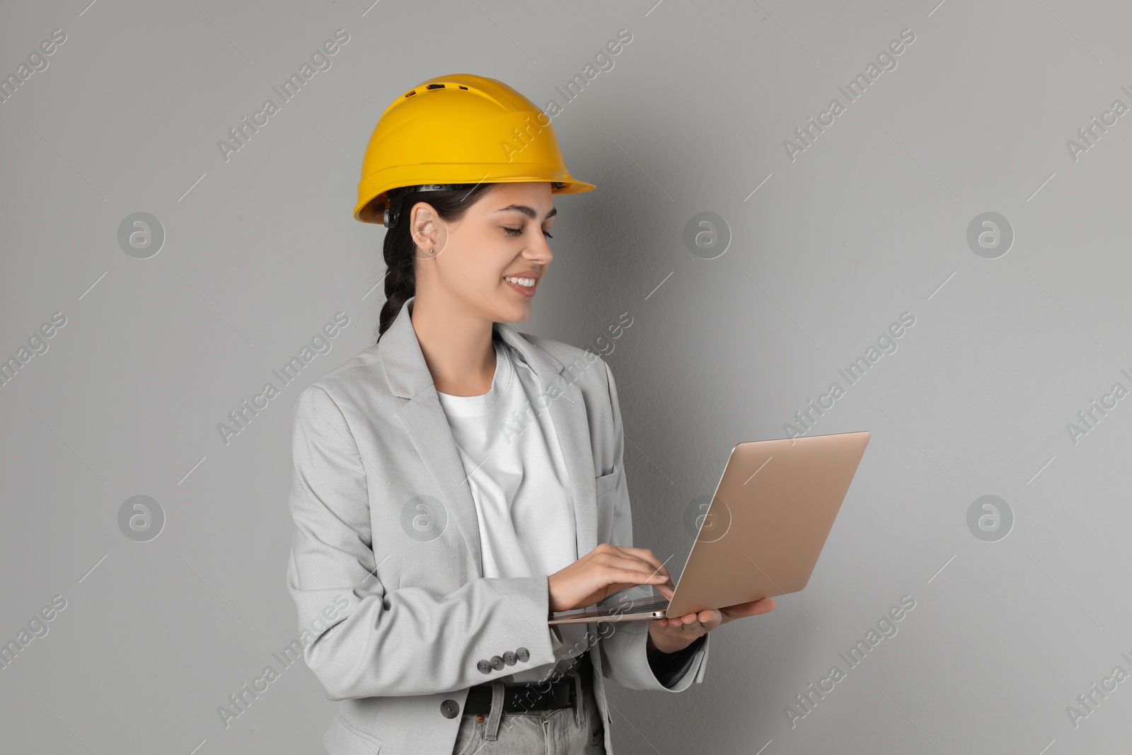 Photo of Engineer in hard hat with laptop on grey background