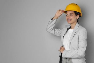 Engineer in hard hat on grey background, space for text