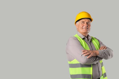 Engineer in hard hat on grey background, space for text