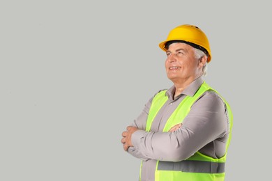 Engineer in hard hat on grey background, space for text