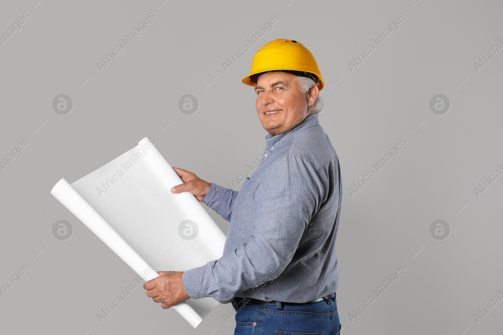 Photo of Engineer in hard hat with draft on grey background