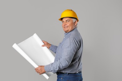 Engineer in hard hat with draft on grey background