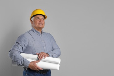 Engineer in hard hat with drafts on grey background, space for text