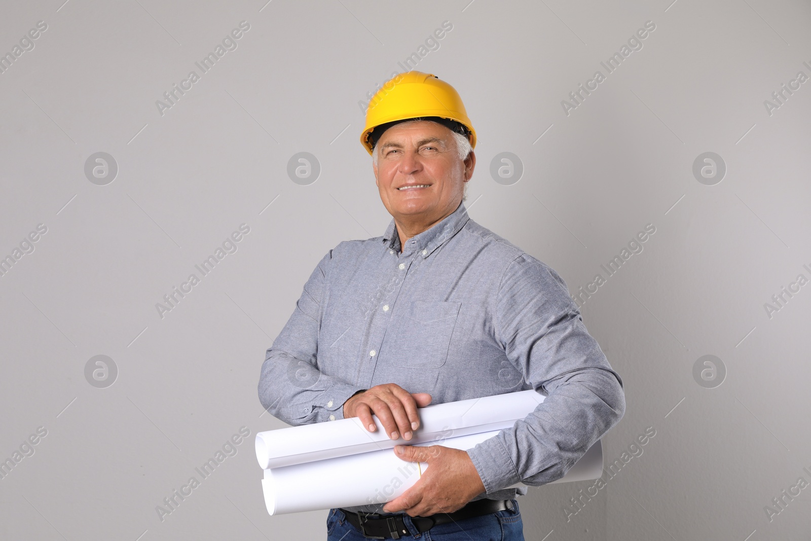 Photo of Engineer in hard hat with drafts on grey background