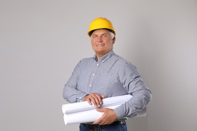 Engineer in hard hat with drafts on grey background