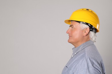 Engineer in hard hat on grey background, space for text