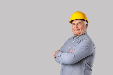 Engineer in hard hat on grey background, space for text