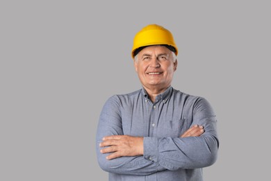 Engineer in hard hat on grey background, space for text