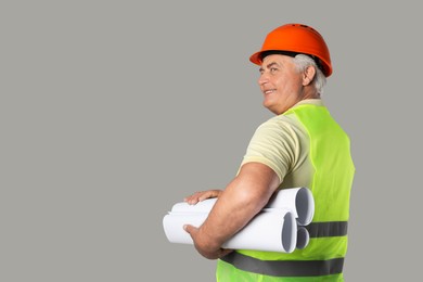 Engineer in hard hat with drafts on grey background, space for text