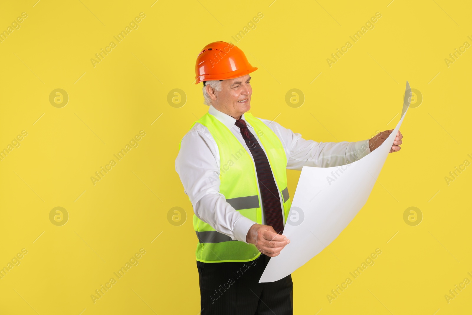 Photo of Engineer in hard hat with draft on yellow background, space for text