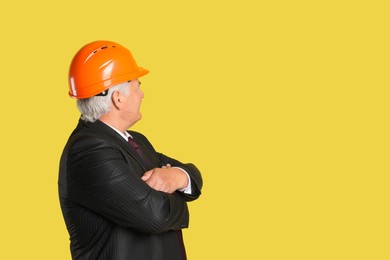 Engineer in hard hat on yellow background, space for text