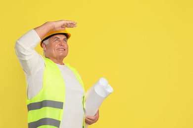 Engineer in hard hat with drafts on yellow background, space for text