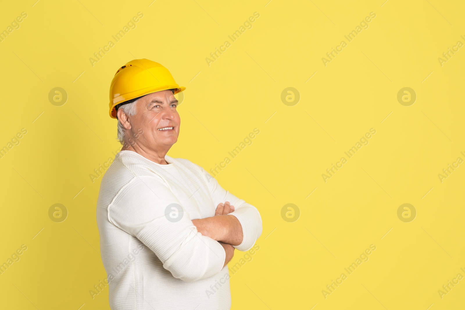 Photo of Engineer in hard hat on yellow background, space for text