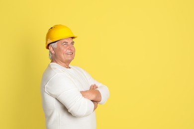 Photo of Engineer in hard hat on yellow background, space for text