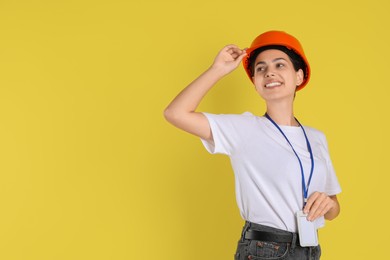 Photo of Engineer in hard hat on yellow background, space for text