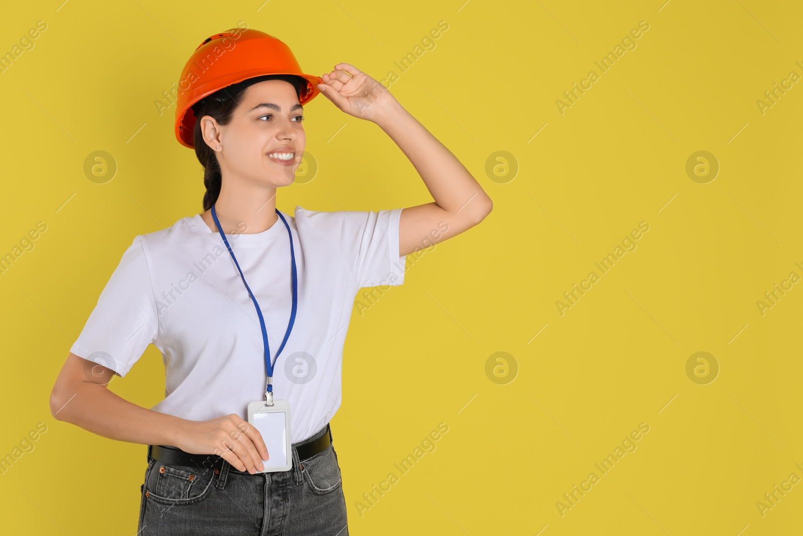 Photo of Engineer in hard hat on yellow background, space for text