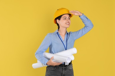 Engineer in hard hat with drafts on yellow background