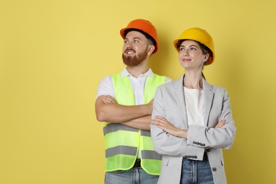 Photo of Engineers in hard hats on yellow background, space for text