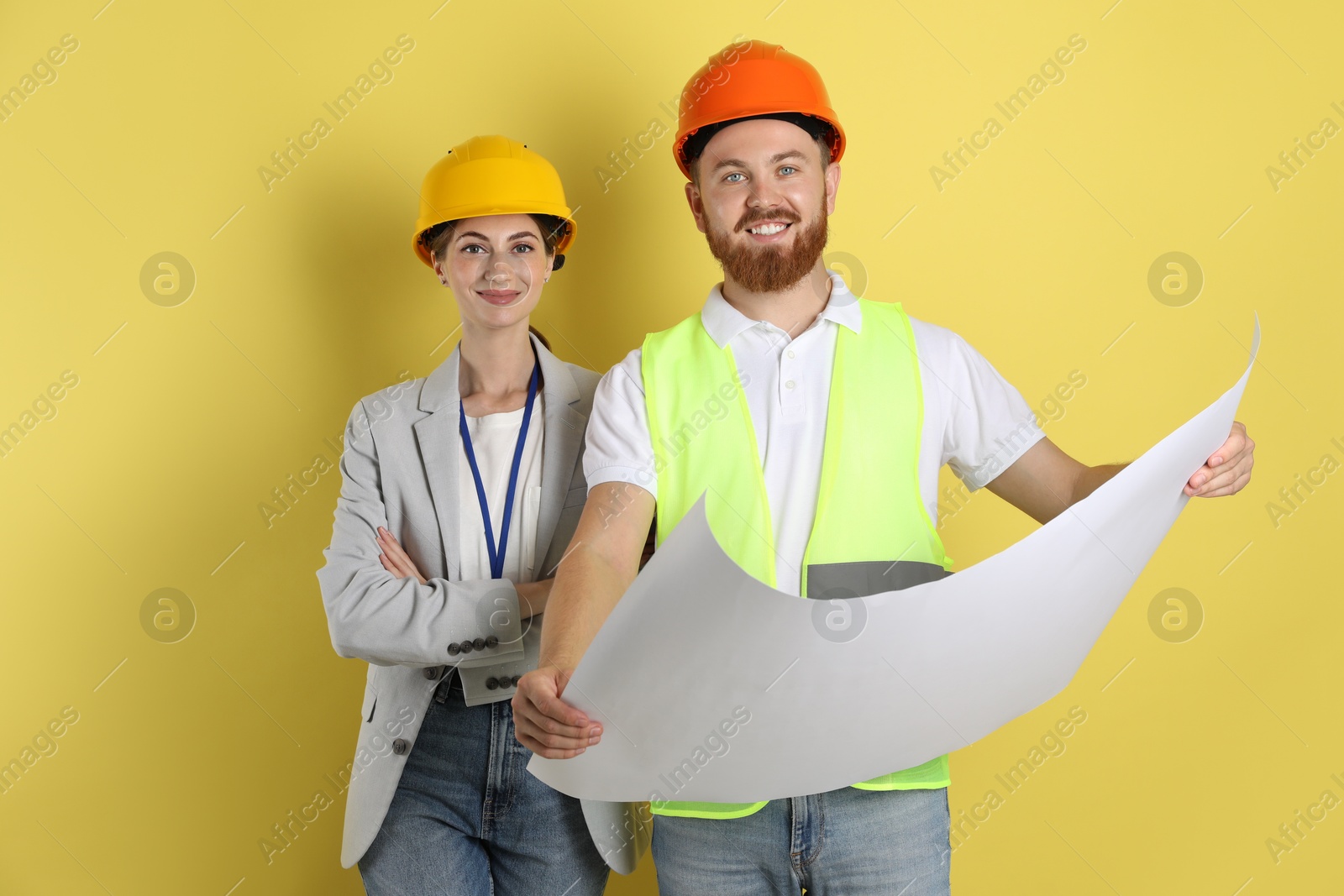 Photo of Engineers in hard hats with draft on yellow background