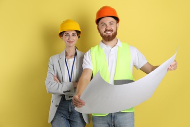 Photo of Engineers in hard hats with draft on yellow background
