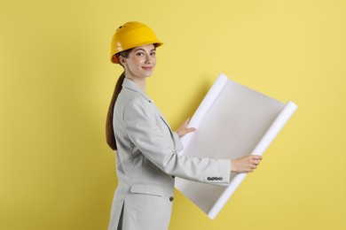 Engineer in hard hat with draft on yellow background