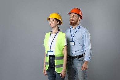 Photo of Engineers in hard hats on grey background, space for text
