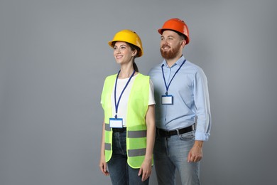 Engineers in hard hats on grey background, space for text