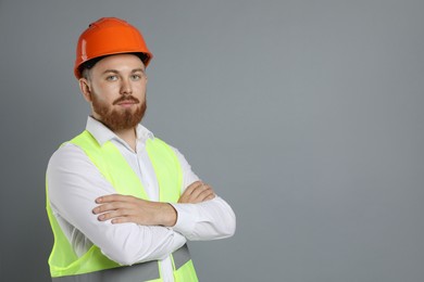 Engineer in hard hat on grey background, space for text