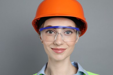 Photo of Engineer in hard hat and goggles on grey background