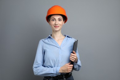 Engineer in hard hat with clipboard on grey background