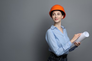 Engineer in hard hat with draft on grey background, space for text