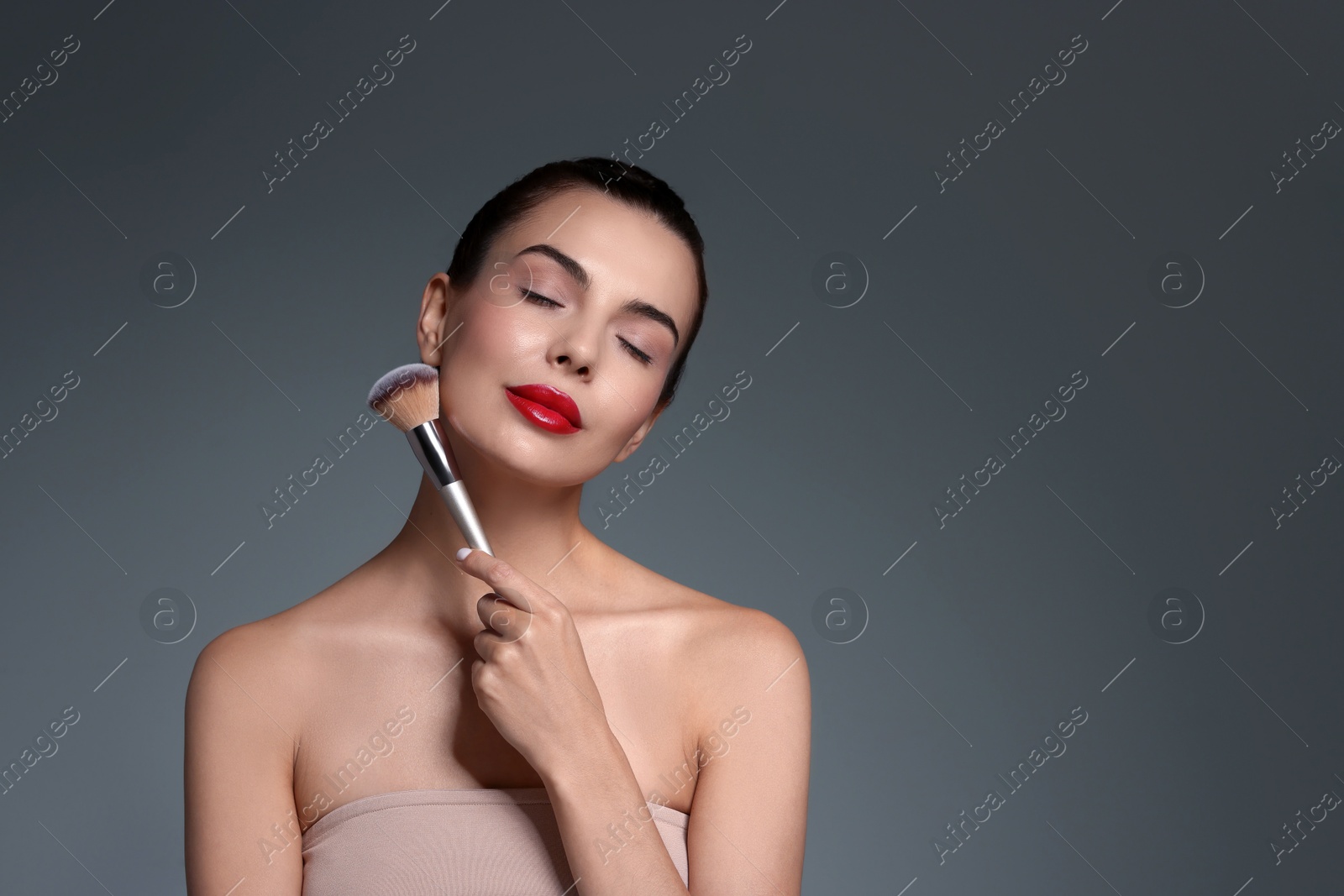 Photo of Beautiful makeup. Attractive woman with brush on grey background, space for text