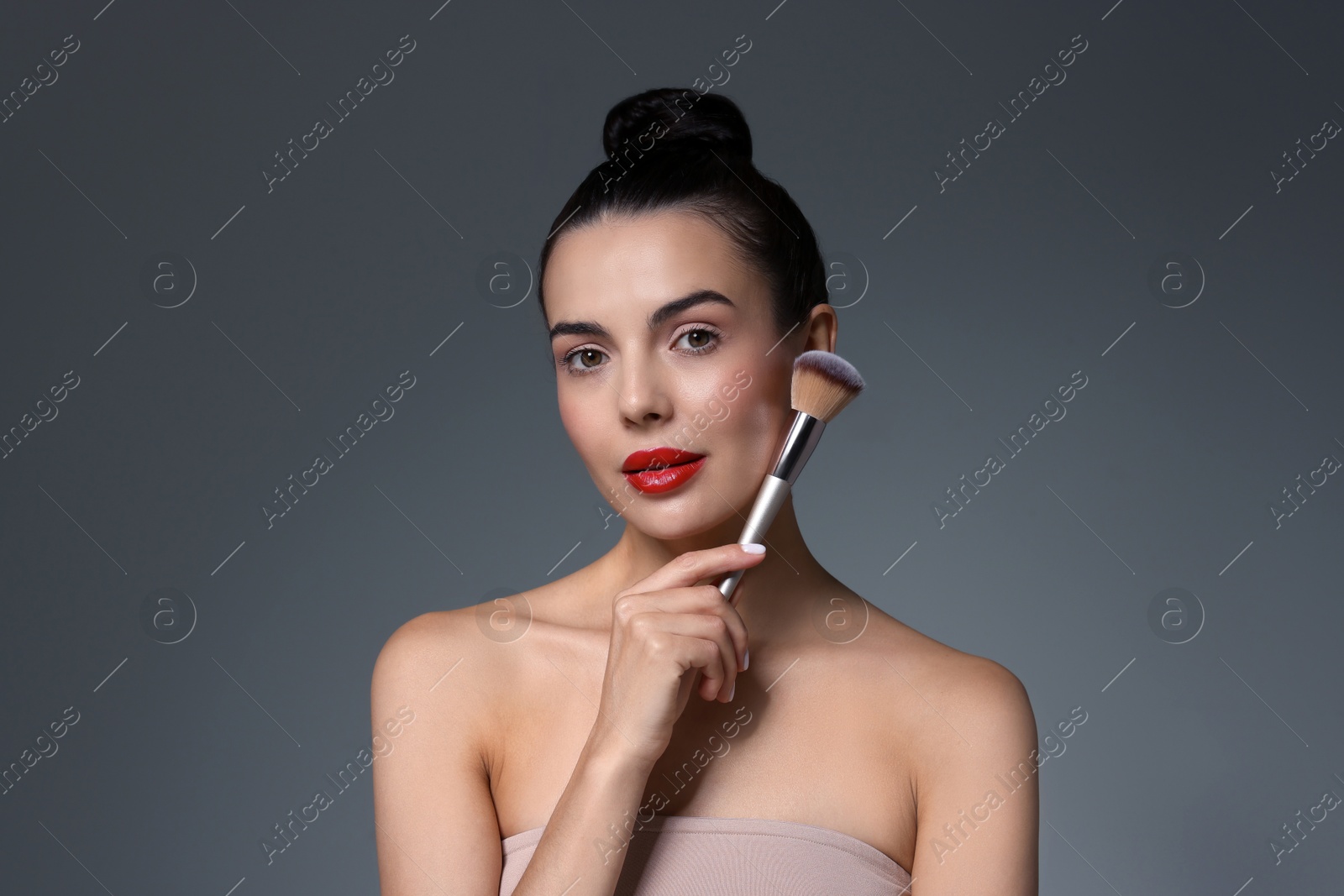 Photo of Beautiful makeup. Attractive woman with brush on grey background