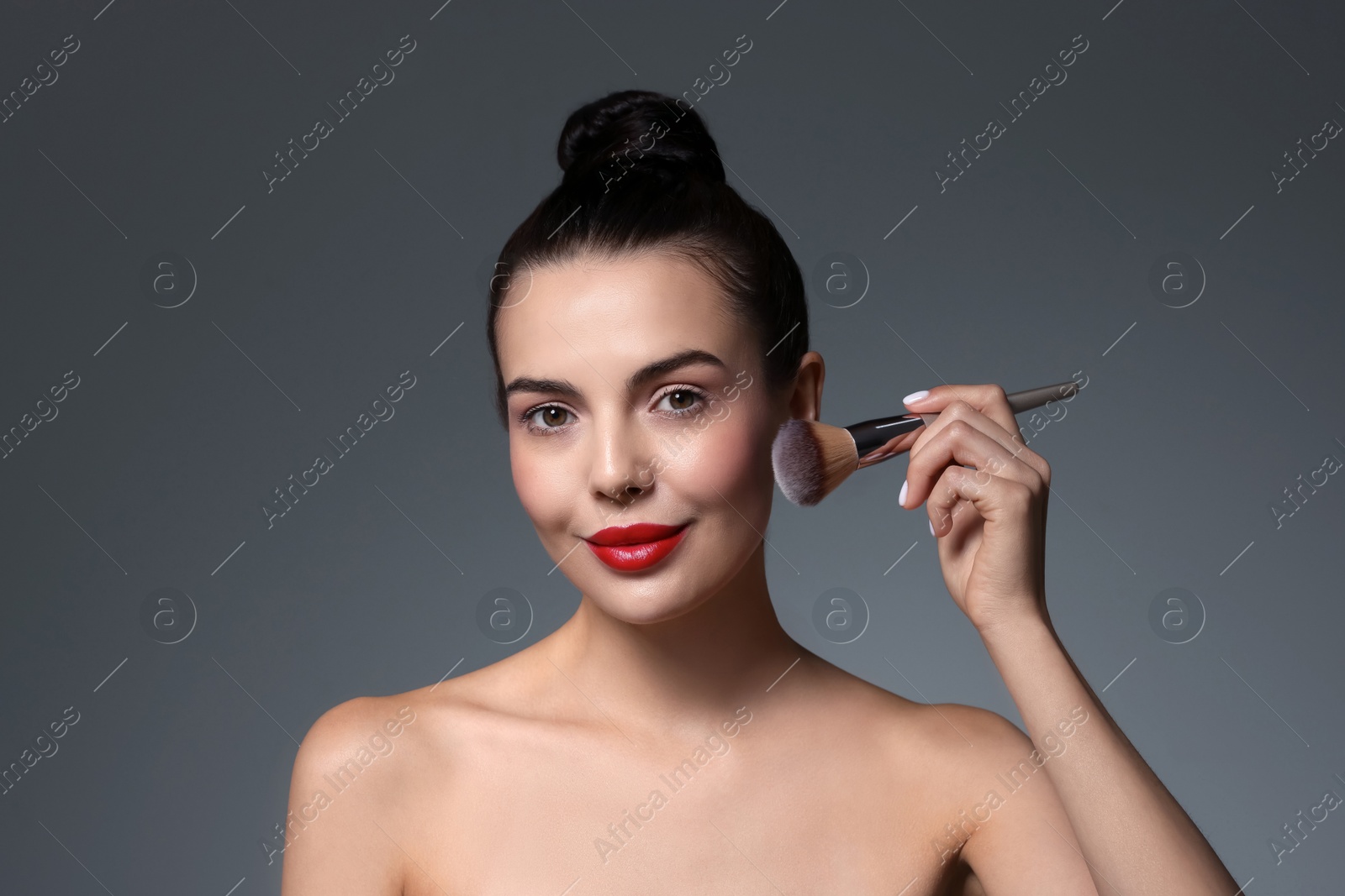 Photo of Beautiful makeup. Attractive woman with brush on grey background