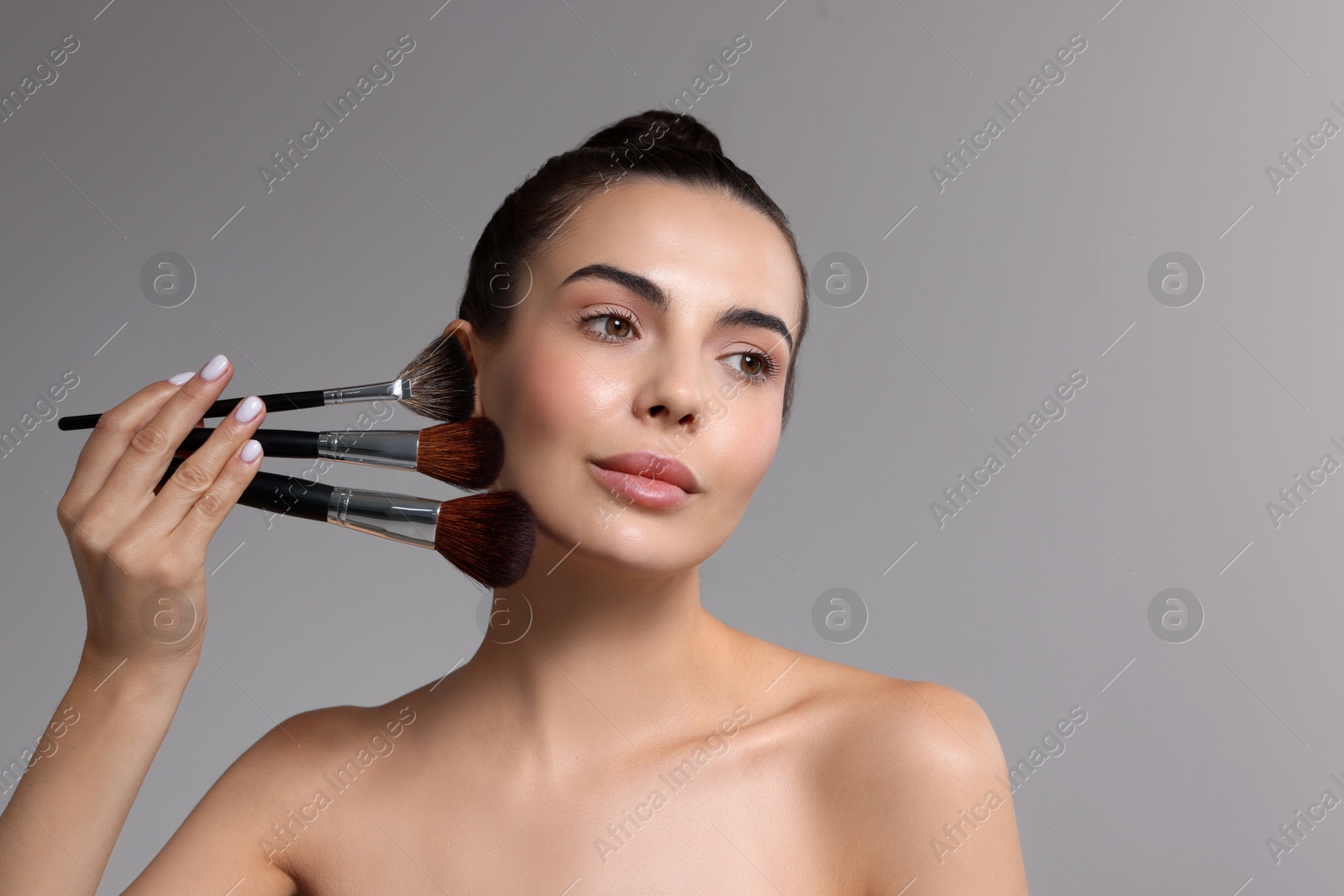 Photo of Beautiful makeup. Attractive woman with brushes on grey background, space for text