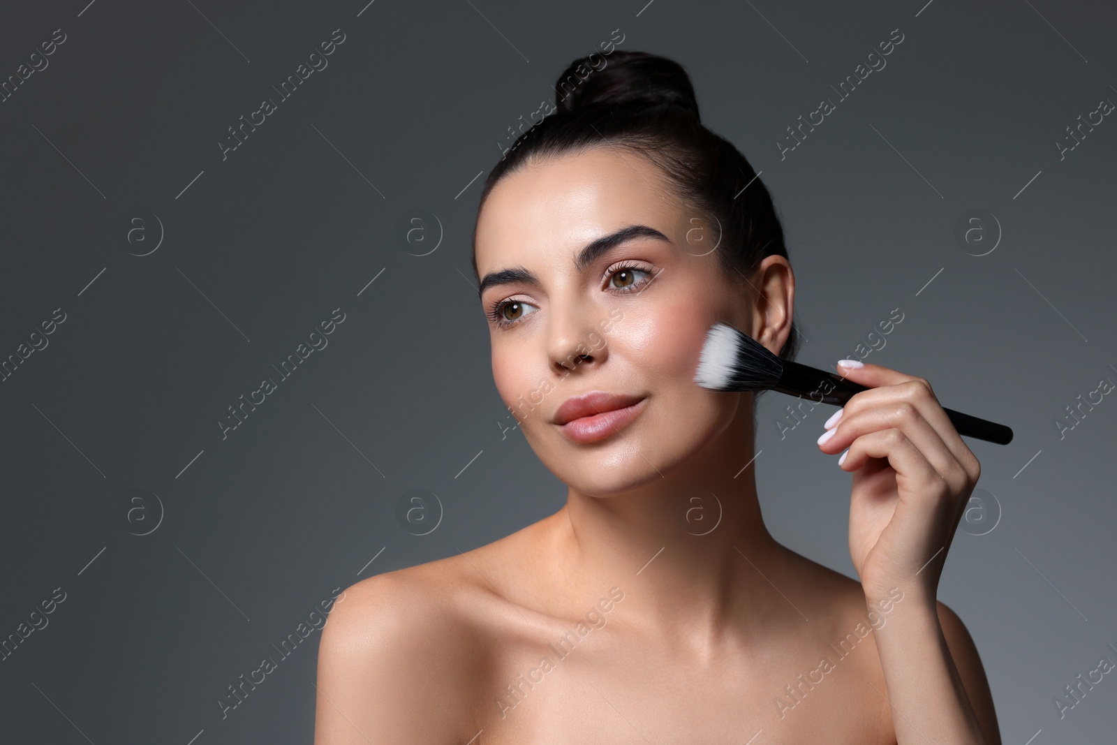 Photo of Beautiful woman with makeup brush on grey background. Space for text